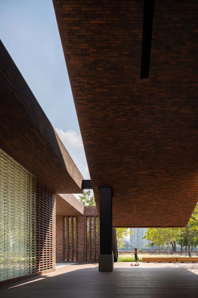 Covered passage framed by variegated brick walls and black steel column with pedestrians visible beyond
