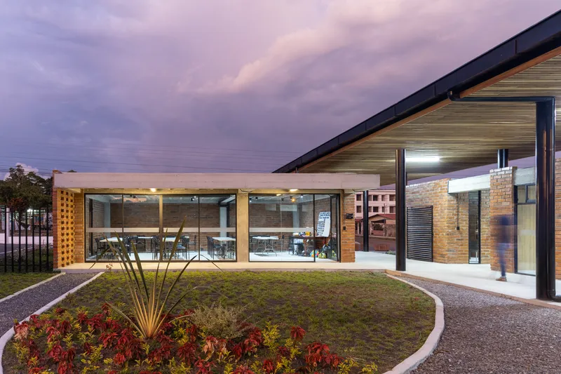 Green roof courtyard with glass-walled dining area and landscape lighting under a purple twilight sky