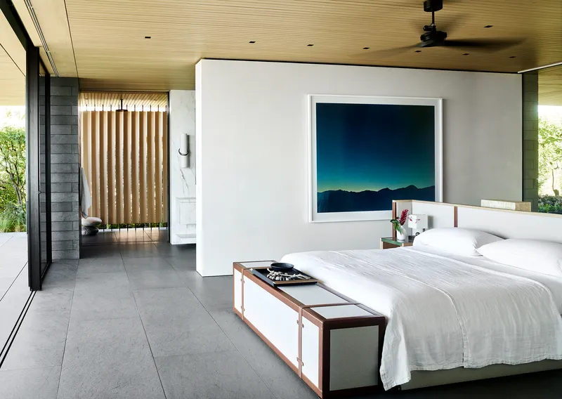 Bedroom with slatted wood ceiling, freestanding white partition, and floor-to-ceiling glass opening to terrace