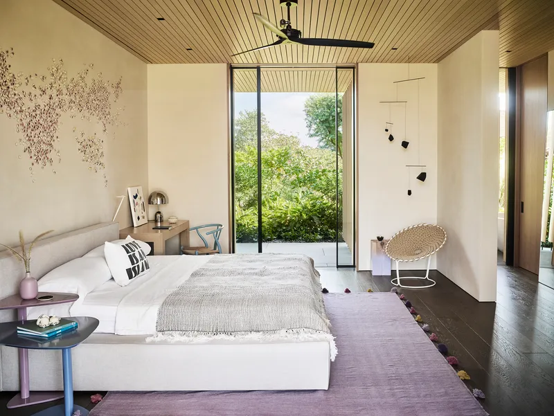 Bedroom with tall glazed door framing view of trees and slatted wood ceiling overhead