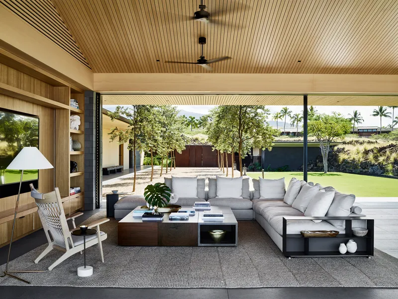 Living area with slat wood ceiling opening through glass walls to planted courtyard beyond