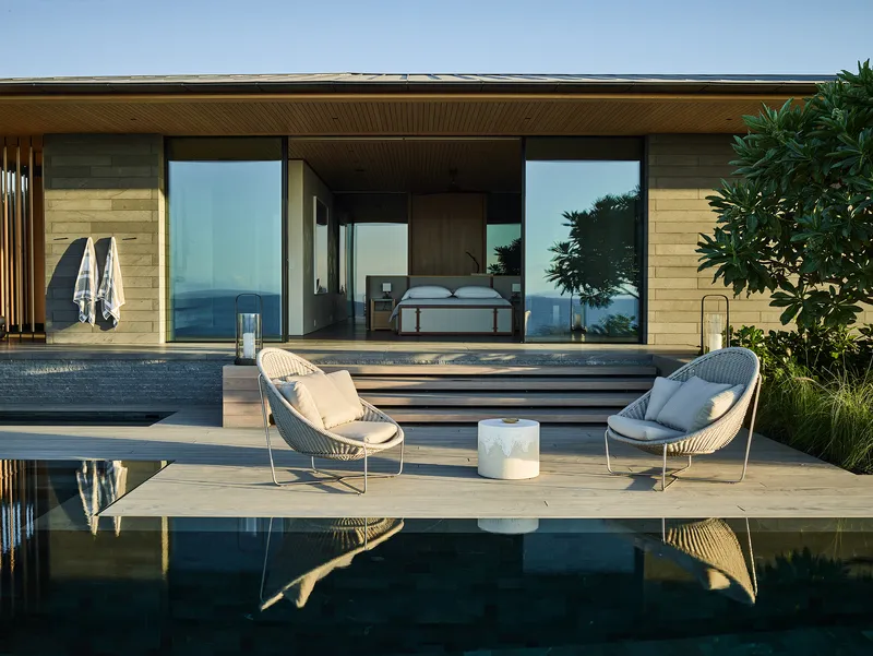 Poolside terrace with timber decking and slatted ceiling opening to a bedroom with ocean views