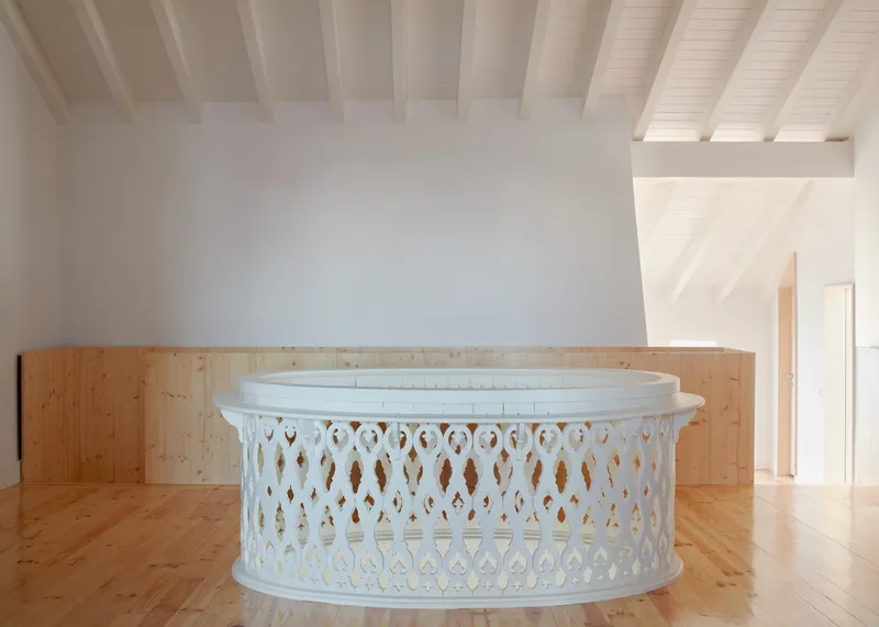 White painted ornamental balustrade with timber backing under an exposed beam ceiling
