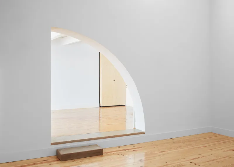 Arched doorway framing a view through to timber closet doors and pine flooring