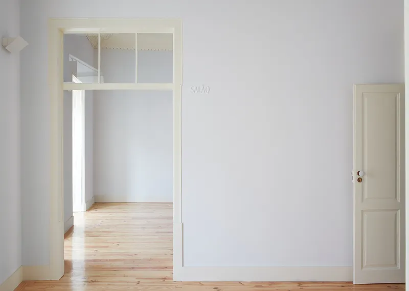 Doorway with transom window framing view into adjacent room with pine floorboards