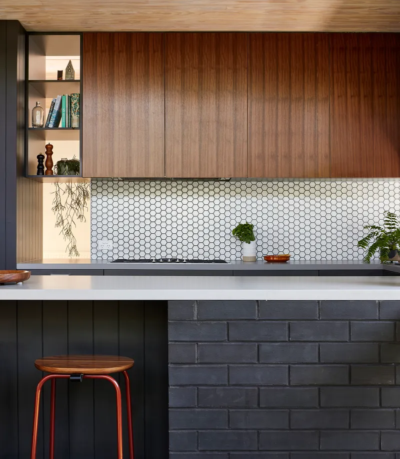 Kitchen counter with white hexagonal mosaic tile backsplash beneath timber cabinetry and open shelving