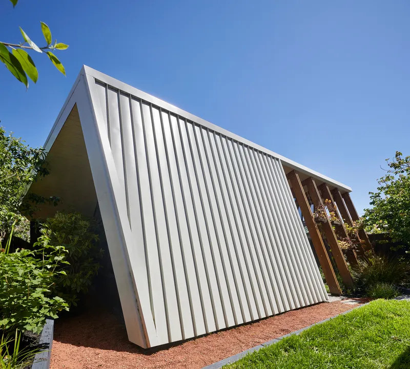Exterior view of the white corrugated metal facade with triangular profile against a clear blue sky