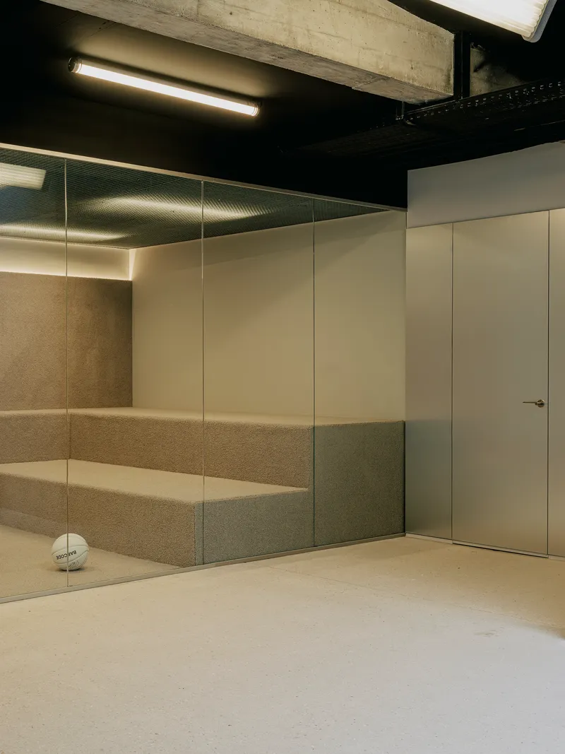 Corner with glass-fronted cork wall niche, flush white door, and black-painted ceiling under concrete beam