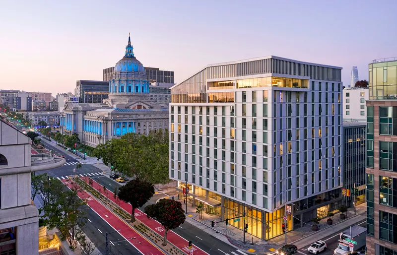 Aerial view of the corner building with its white facade and glass base at twilight