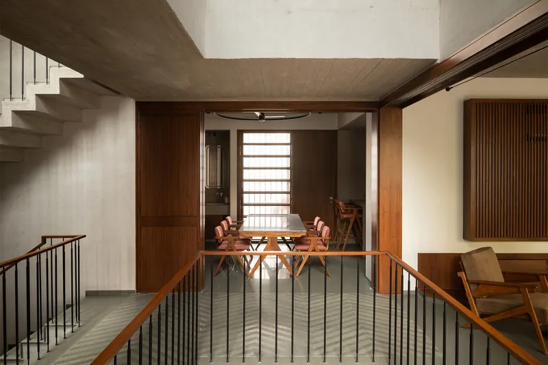 View across stair landing toward timber-framed dining area with horizontal slatted screens