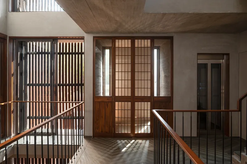 Stairwell landing with gridded timber screens and translucent sliding doors filtering daylight