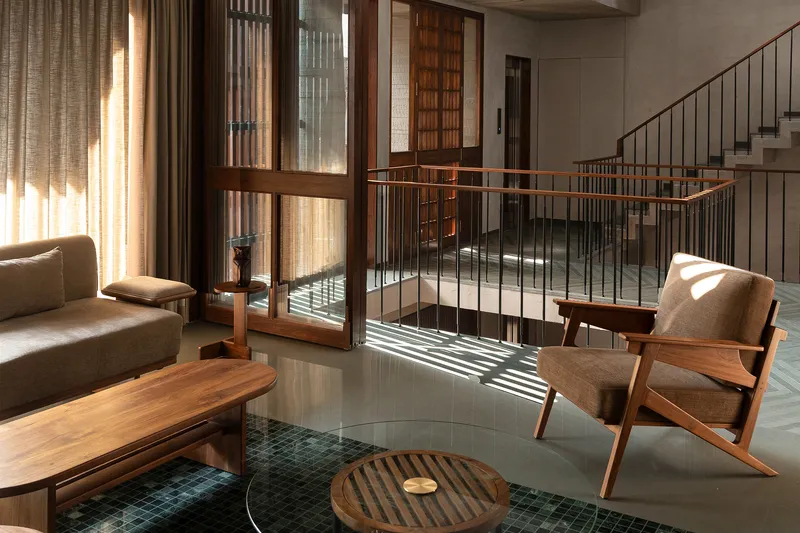 Living room with a sunken tile pool, metal railing, and sunlight streaming through timber-framed doors