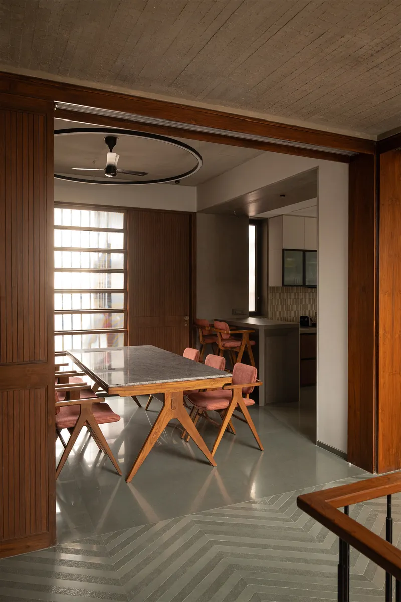 View through a curved timber portal into the dining room with herringbone flooring at the threshold