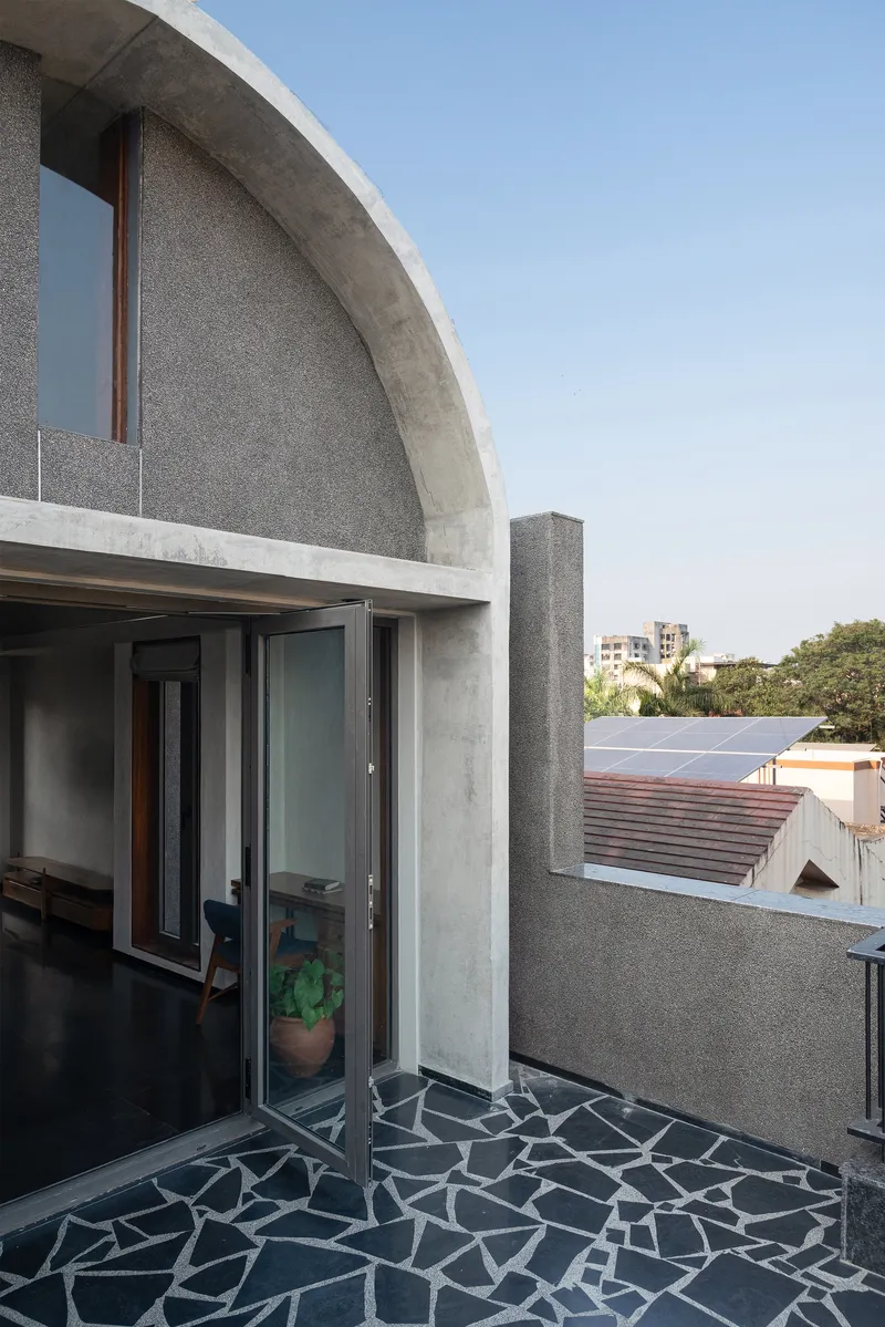 Rooftop terrace with concrete barrel vault and broken tile mosaic floor under a clear sky