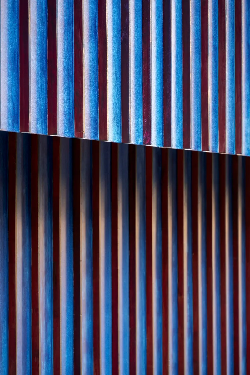 Blue-tinted vertical timber slats with a horizontal shadow line dividing the facade