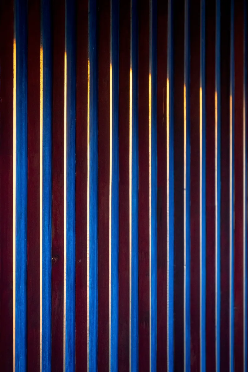 Vertical timber slat screen with warm backlighting glowing through the gaps at night