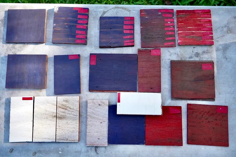 Array of wood sample boards on concrete showing gradations from dark stain to bare timber