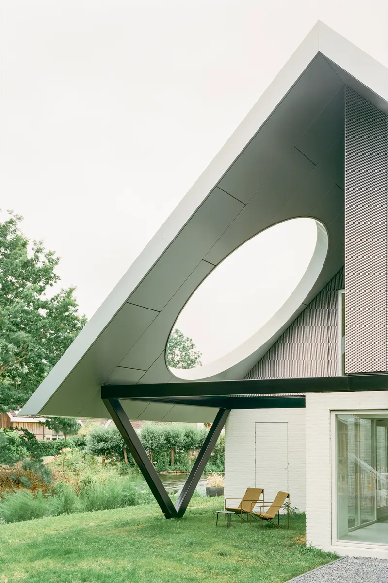 Perforated metal roof canopy with circular aperture and angled steel support over terrace