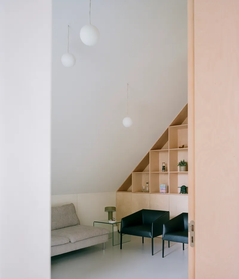 Interior view through doorway showing plywood shelving under pitched ceiling with pendant lights