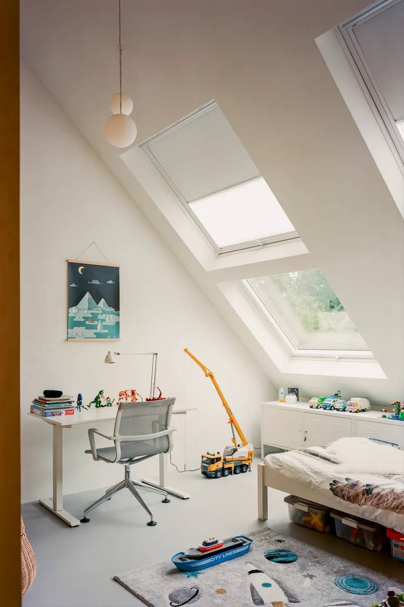 Upper-level bedroom with roof skylights and scattered toys on the floor