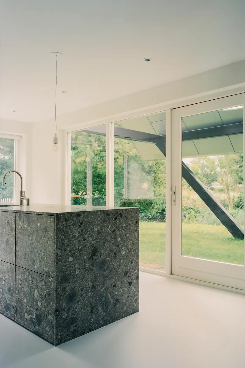 Kitchen with dark stone island and pendant light facing glazed doors to the garden