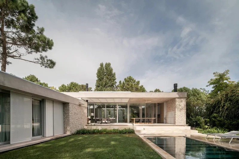 Garden view showing the glass-walled pavilion and reflecting pool surrounded by lawn and pines