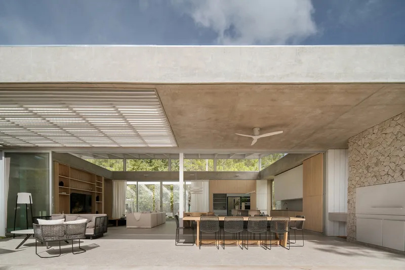Covered terrace with plywood ceiling and stone accent wall framing the interior living and dining spaces