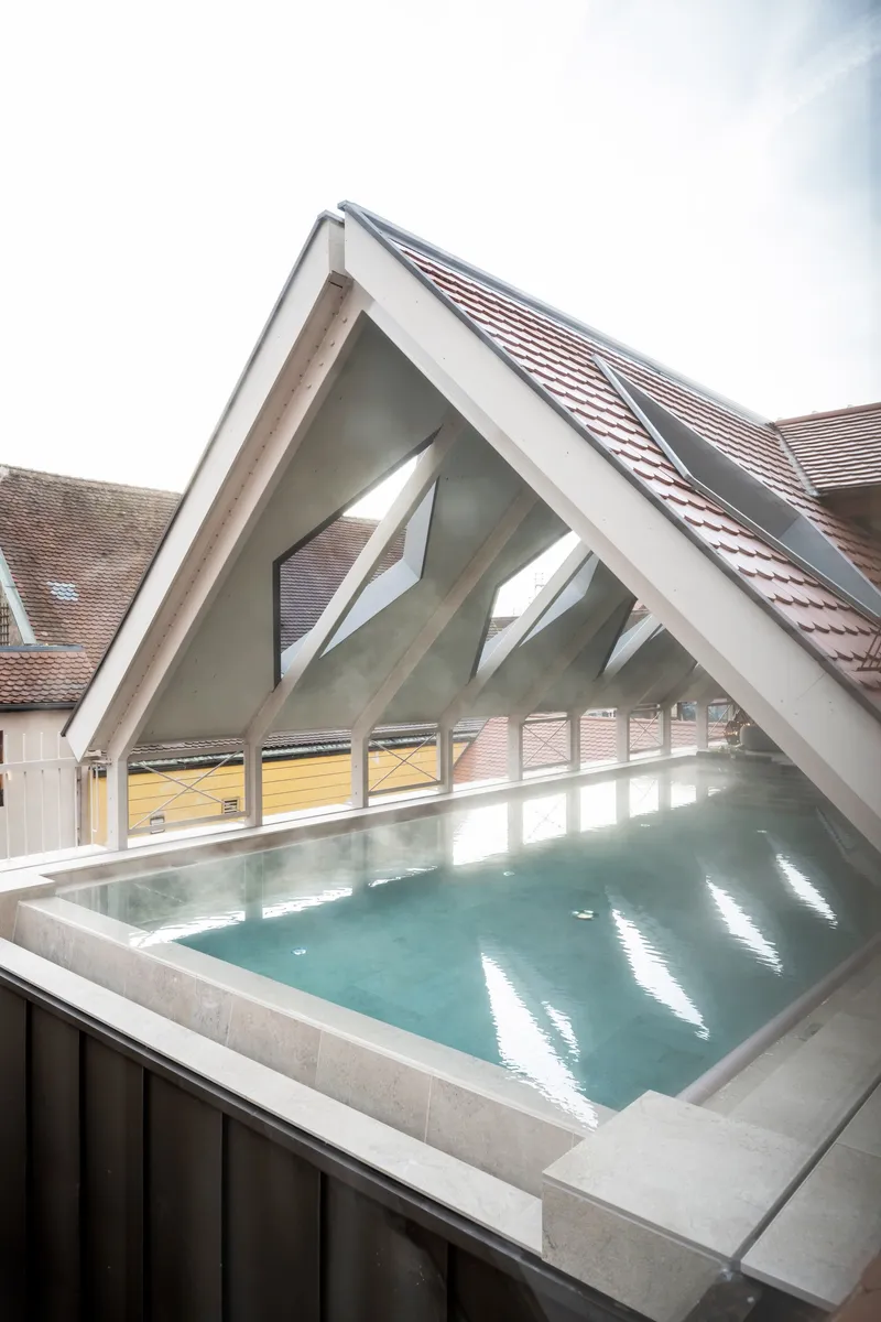 Rooftop pool with concrete edge under a white-painted timber gable and tiled roof