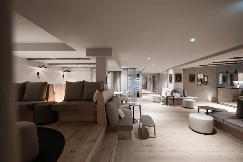 Open lounge area with upholstered seating clusters and wide timber floor under recessed ceiling lighting