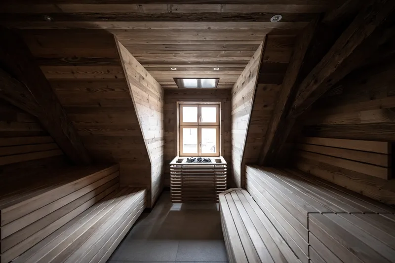 Sauna room with horizontal timber benching, angled walls, and a window at the far end