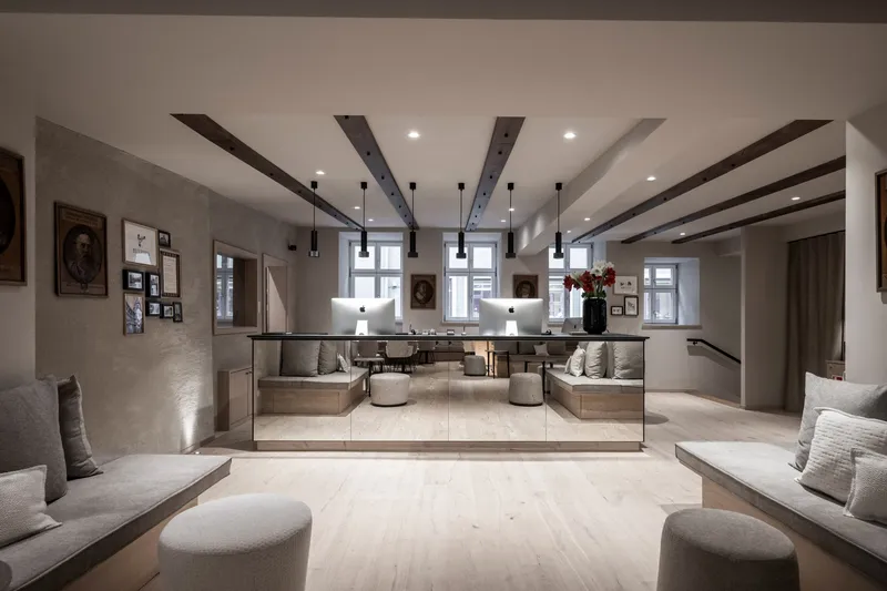 Reception lobby with mirrored front desk and symmetrical seating under exposed timber ceiling beams