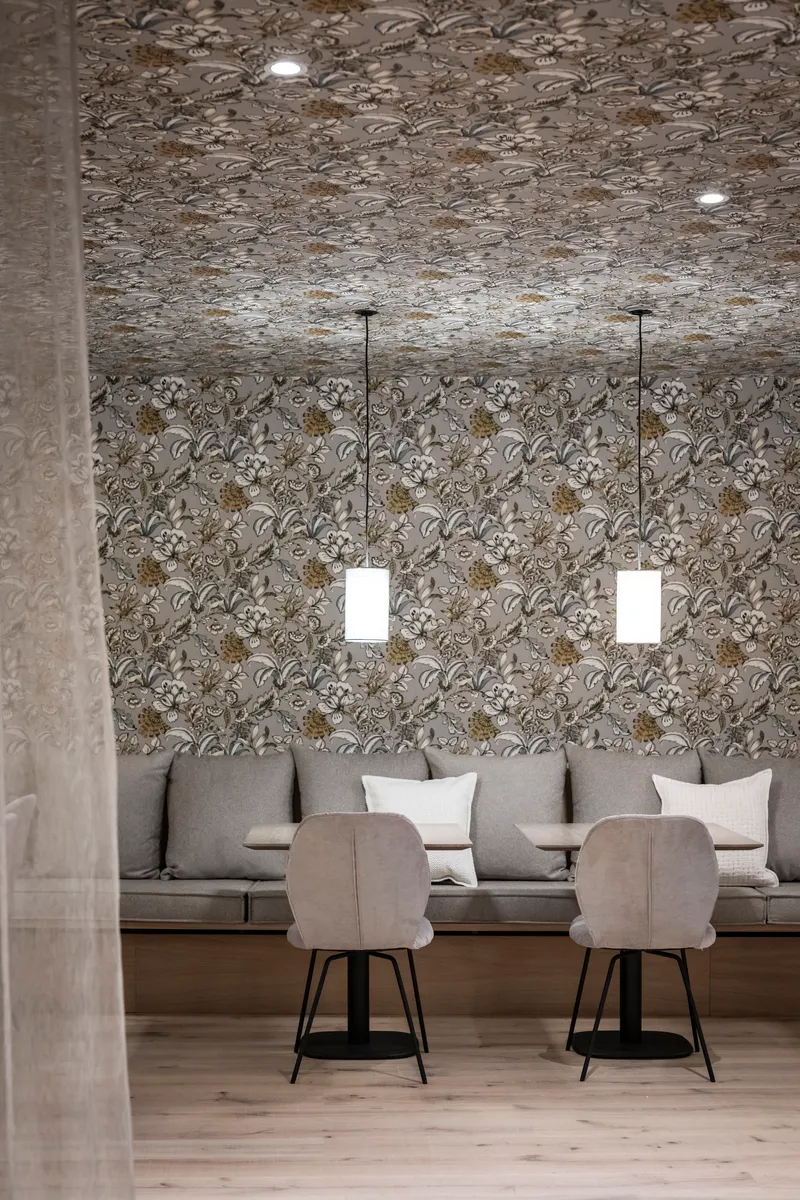 Seating niche with floral wallpaper covering walls and ceiling flanked by two pendant lights