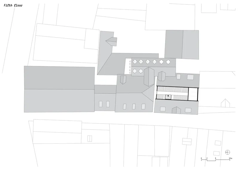 Fifth floor plan drawing showing irregularly shaped volumes with interior furnishings and surrounding context
