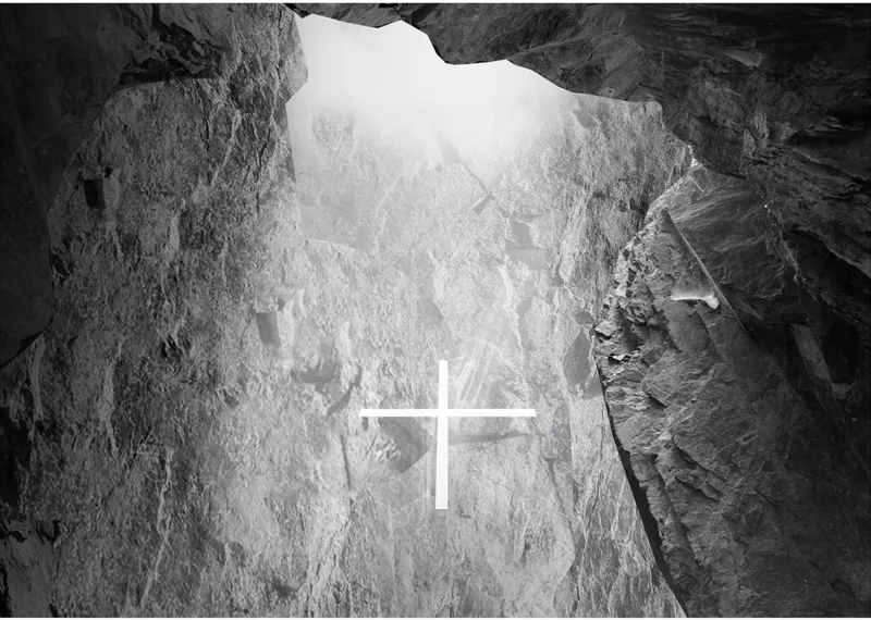 A glowing glass cross illuminates the rock-hewn chapel interior.
