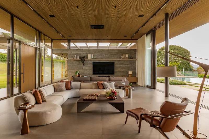 Living room with wood-paneled ceiling and full-height glazing opening to landscaped terrace