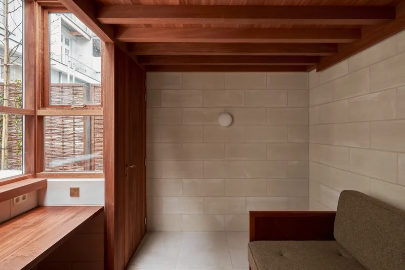 Corner view showing timber door, exposed ceiling joists, and limestone block wall with spherical wall sconce