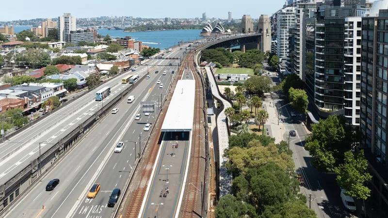 Long view of the white ribbon bridge spanning above railway tracks and highway with harbor in distance