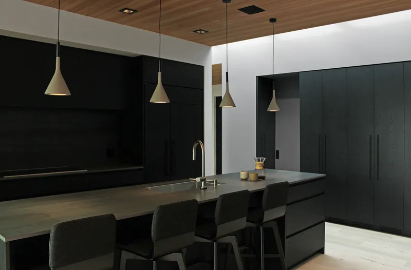 Kitchen island with black cabinetry and brass pendant lights beneath wood ceiling