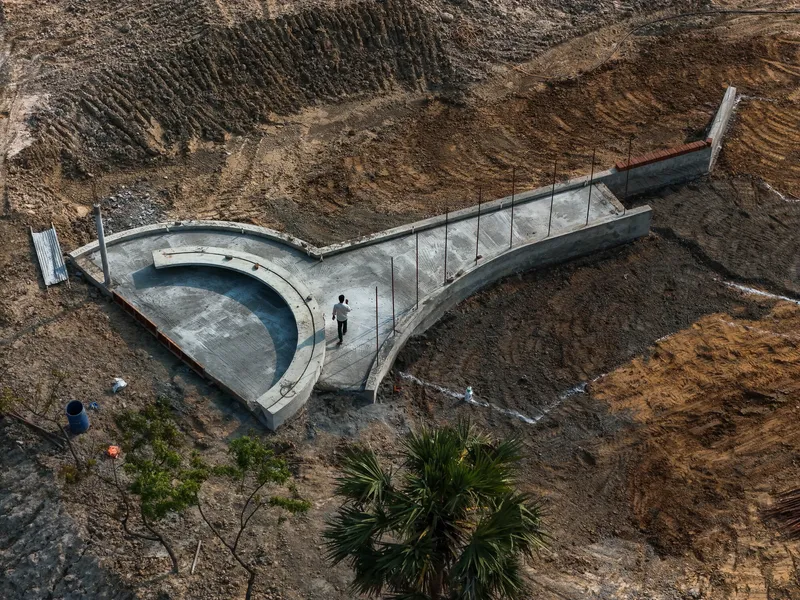 Drone view of concrete stepped pool platform carved into dry hillside terrain
