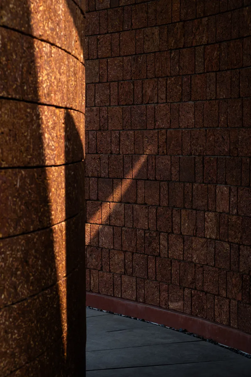 Corner detail of textured laterite brick walls catching warm afternoon sunlight and shadow