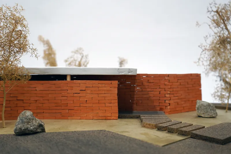 Physical model of red brick entrance wall with concrete roof slab and stepping stones