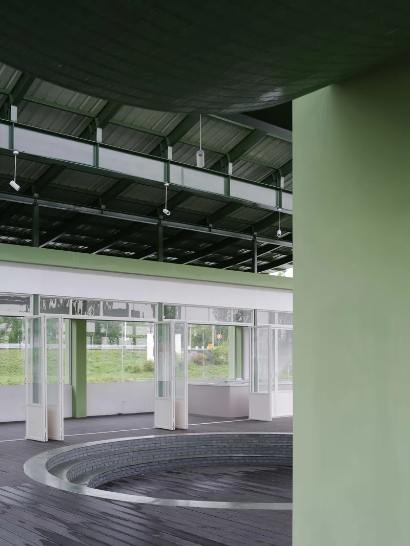 Interior space with circular timber deck around a recessed pool under exposed steel structure
