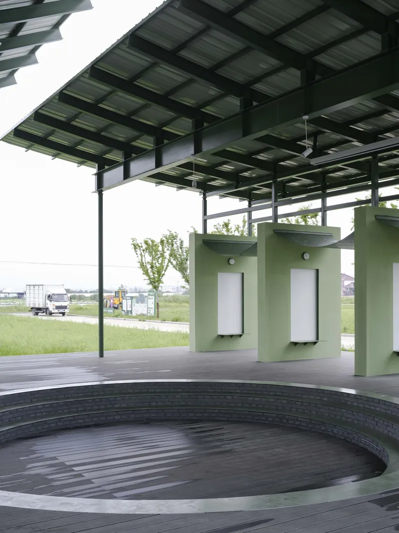 Circular timber deck with green cylindrical kiosks beneath layered solar panel canopy in daylight