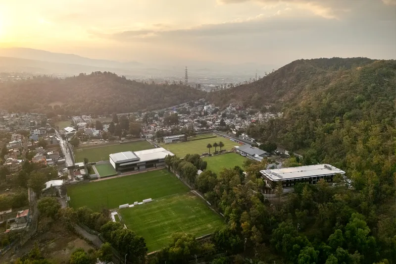 Aerial view of parallel training fields nestled between forested hills at sunset