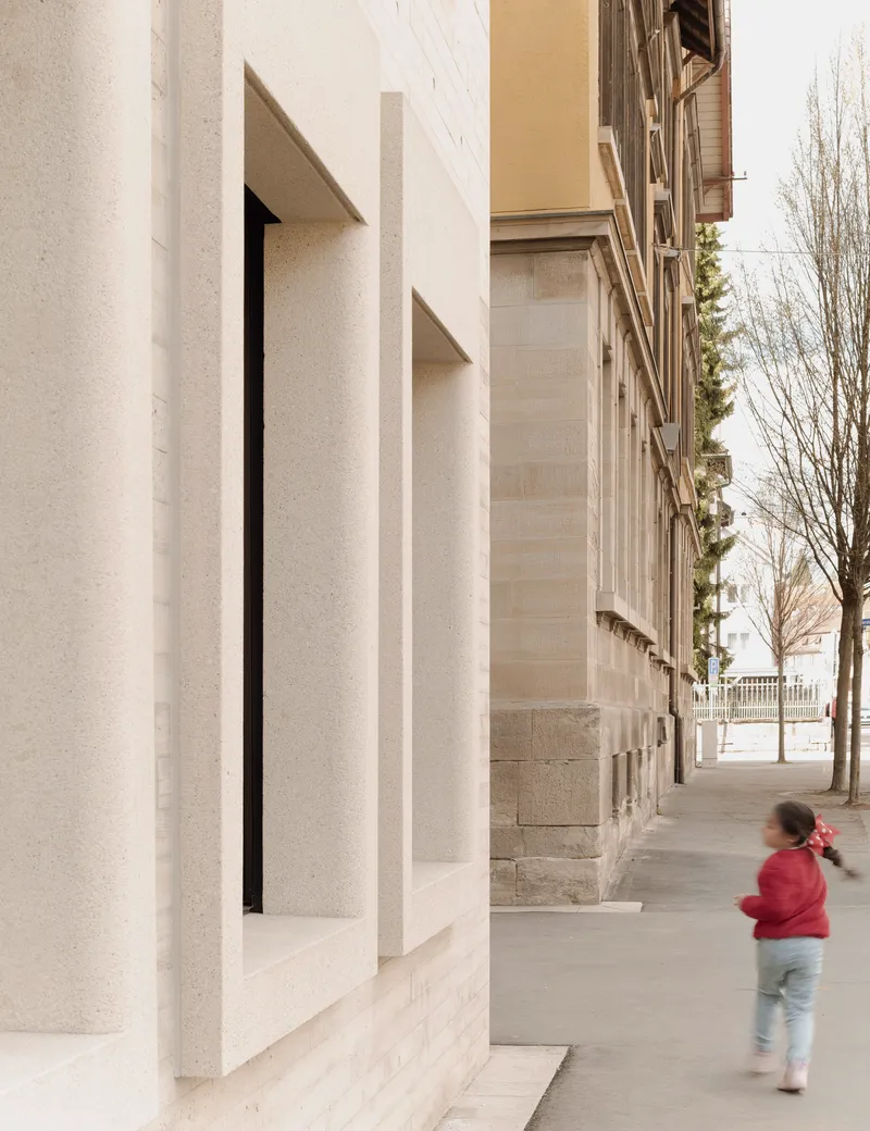 Deep window reveal at ground level with a child walking past on the sidewalk