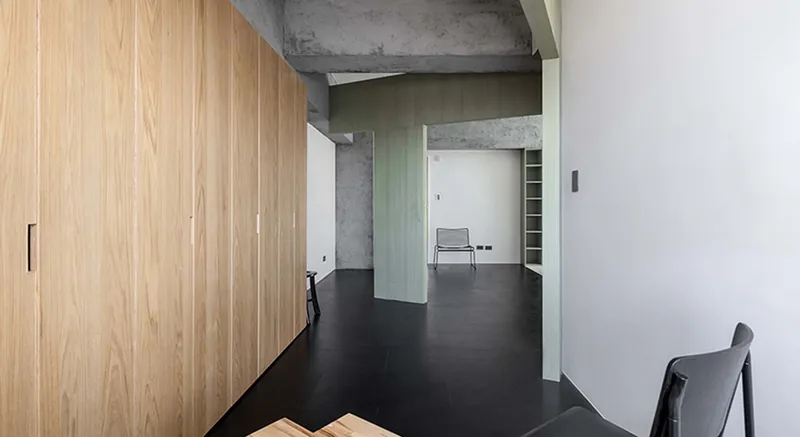 Corridor with timber storage wall and pale green partition framing views through connected interior spaces