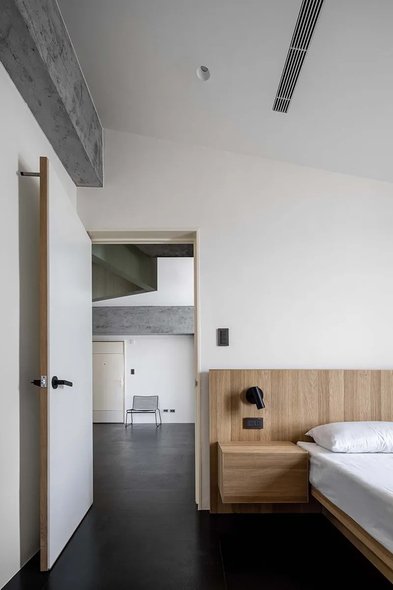 Bedroom with timber platform bed and view through doorway to adjacent spaces