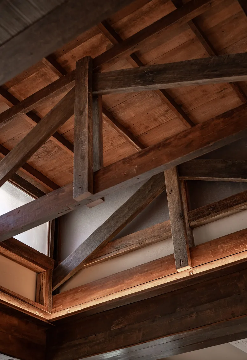 Exposed timber ceiling structure with crossed beams and tongue-and-groove wood planking