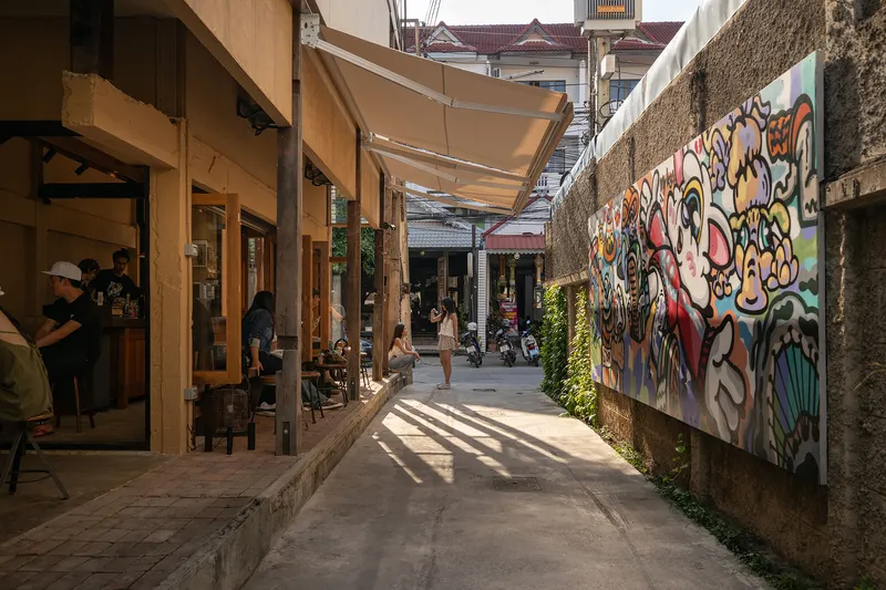 Open-air courtyard passage with timber-framed cafe seating and graffiti-covered concrete wall
