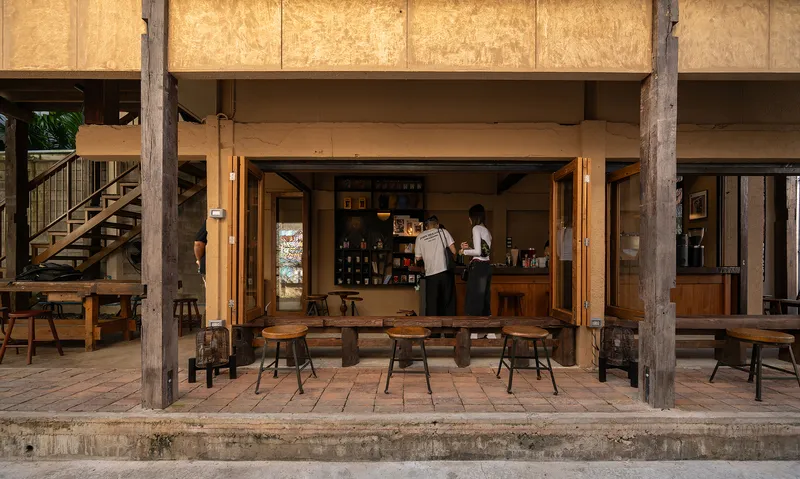Ground-floor cafe counter with folding timber doors opening to outdoor seating under reclaimed timber beams